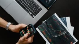 Ilustrasi kalender yang menandai tanggal-tanggal penting di bursa saham, menggambarkan momen krusial bagi investor untuk memantau jadwal pembagian dividen perusahaan. Tangan yang sedang memegang grafik saham menunjukkan analisis data yang cermat sebelum mengambil keputusan investasi.
