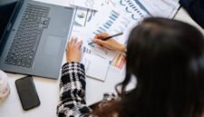 Seorang profesional tengah menganalisis detail laporan tahunan perusahaan yang terhampar di meja, menunjukkan kompleksitas dan kekayaan informasi yang terkandung dalam dokumen penting tersebut. Laporan ini bukan sekadar kumpulan angka, melainkan cerminan strategi dan perjalanan bisnis selama setahun penuh.