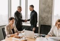 Sebuah adegan menunjukkan jabat tangan erat antara pebisnis di sebuah kantor modern yang mencerminkan kolaborasi dan kesepakatan penting terkait investasi atau penambahan modal. Latar belakang kota yang sibuk melambangkan dinamika ekonomi dan peluang pertumbuhan yang akan dibentuk dari keputusan strategis ini.