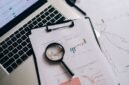 Seorang profesional tengah menganalisis laporan keuangan dan grafik saham, merepresentasikan proses mendalam dalam analisis fundamental untuk mengambil keputusan investasi yang cerdas. Fokus pada data dan kinerja perusahaan adalah kunci untuk investasi jangka panjang yang sukses.