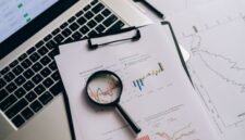 Seorang profesional tengah menganalisis laporan keuangan dan grafik saham, merepresentasikan proses mendalam dalam analisis fundamental untuk mengambil keputusan investasi yang cerdas. Fokus pada data dan kinerja perusahaan adalah kunci untuk investasi jangka panjang yang sukses.