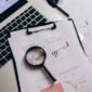 Seorang profesional tengah menganalisis laporan keuangan dan grafik saham, merepresentasikan proses mendalam dalam analisis fundamental untuk mengambil keputusan investasi yang cerdas. Fokus pada data dan kinerja perusahaan adalah kunci untuk investasi jangka panjang yang sukses.