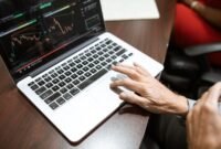Grafik kompleks yang menunjukkan fluktuasi harga saham di bursa, dengan tangan seseorang sedang menganalisis data keuangan pada layar, menggambarkan upaya memahami valuasi saham di tengah dinamika pasar.