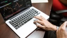 Grafik kompleks yang menunjukkan fluktuasi harga saham di bursa, dengan tangan seseorang sedang menganalisis data keuangan pada layar, menggambarkan upaya memahami valuasi saham di tengah dinamika pasar.
