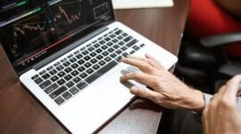 Grafik kompleks yang menunjukkan fluktuasi harga saham di bursa, dengan tangan seseorang sedang menganalisis data keuangan pada layar, menggambarkan upaya memahami valuasi saham di tengah dinamika pasar.