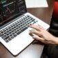 Grafik kompleks yang menunjukkan fluktuasi harga saham di bursa, dengan tangan seseorang sedang menganalisis data keuangan pada layar, menggambarkan upaya memahami valuasi saham di tengah dinamika pasar.
