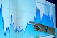 Seorang investor tengah memantau pergerakan grafik harga saham di layar, mencerminkan dinamika pasar modal yang kompleks. Data visual seperti ini menjadi panduan penting bagi setiap individu dalam membuat keputusan investasi yang tepat.