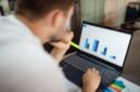 Seorang pebisnis sedang menganalisis data keuangan yang ditampilkan pada grafik pertumbuhan, menunjukkan pentingnya evaluasi cermat terhadap rencana penambahan modal sebuah perusahaan untuk memahami potensi dampaknya di masa depan.