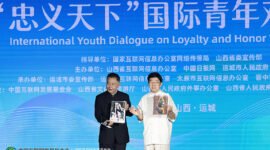 Li Zijun (right), a scholar of the Chinese Theatre Literature Society, displays a photo of his grandfather, Li Hongchun, portraying the legendary Chinese figure Guan Gong during the International Youth Dialogue on Loyalty and Honor Without Borders in Yuncheng, Shanxi province, on Wednesday. [Photo by Zhu Xingxin/China Daily]