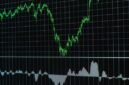 Grafik dan data digital yang ditampilkan di layar bursa efek ini melambangkan arus informasi transparan yang penting bagi setiap investor. Keterbukaan data memungkinkan pengambilan keputusan investasi yang tepat.